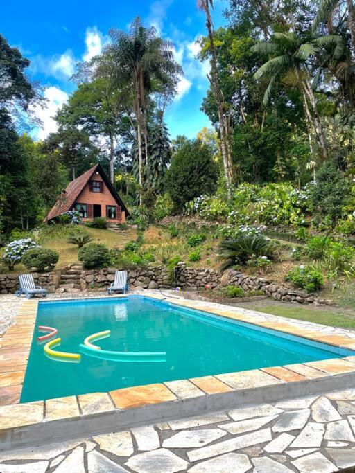 einen Pool mit zwei Stühlen und ein Haus in der Unterkunft Morro Azul chalés in Timbó