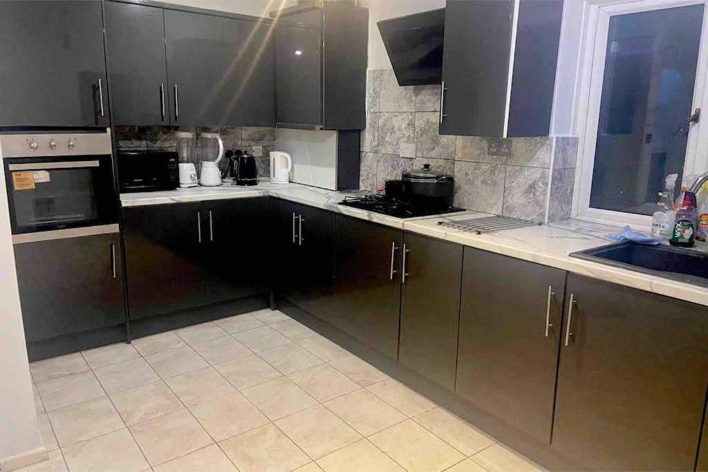 a kitchen with dark brown cabinets and a sink at Liverpool Recently Refurbished Spacious House in Liverpool