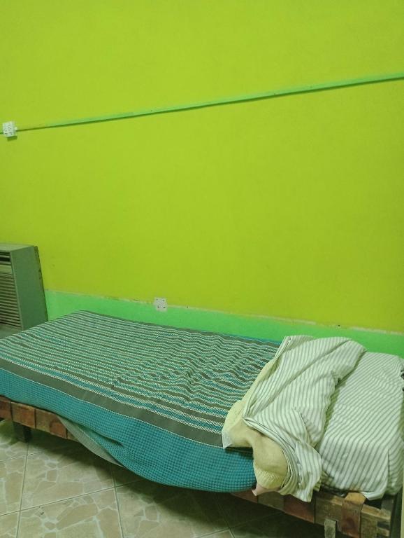 uma cama num quarto com uma parede verde em Camas para descansar en habitación compartida em San Carlos de Bariloche