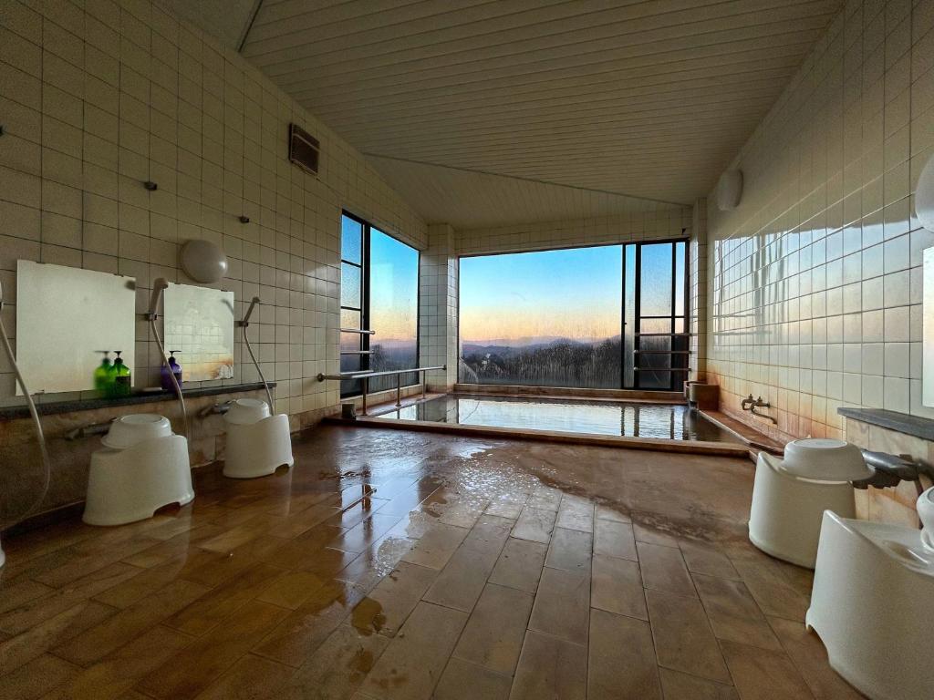 - une grande salle de bains avec une grande fenêtre, des lavabos et des toilettes dans l'établissement Tomiya Ryokan, à Myōkō