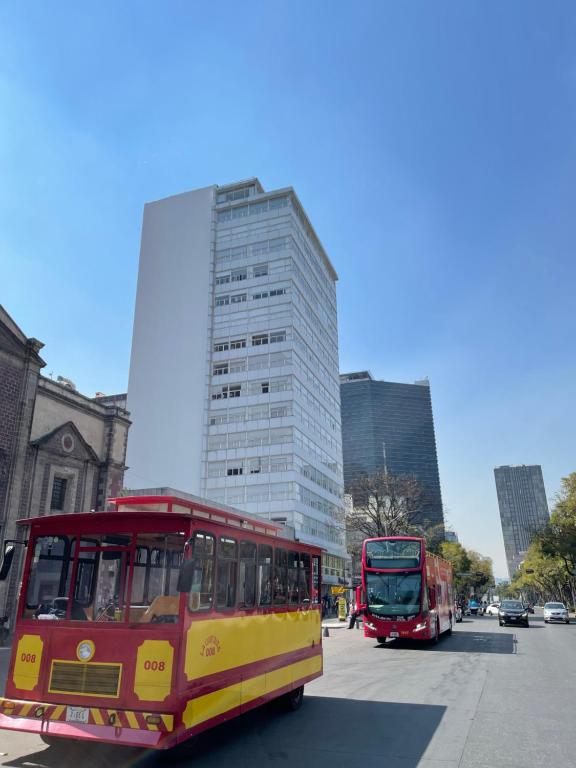 two buses driving down a street in a city at Carso Alameda Premium Apartments in Mexico City