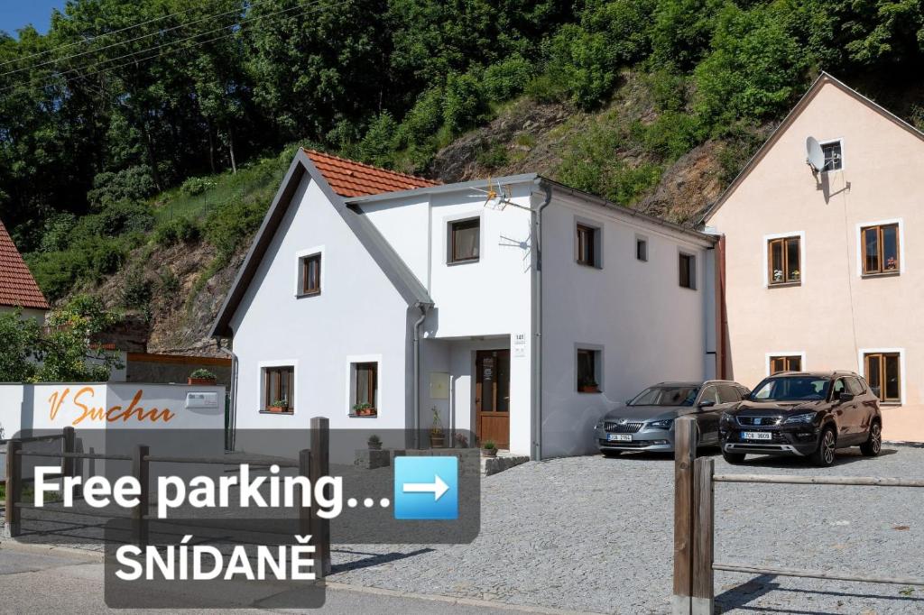 a white house with cars parked in a parking lot at Penzion V Suchu in Český Krumlov