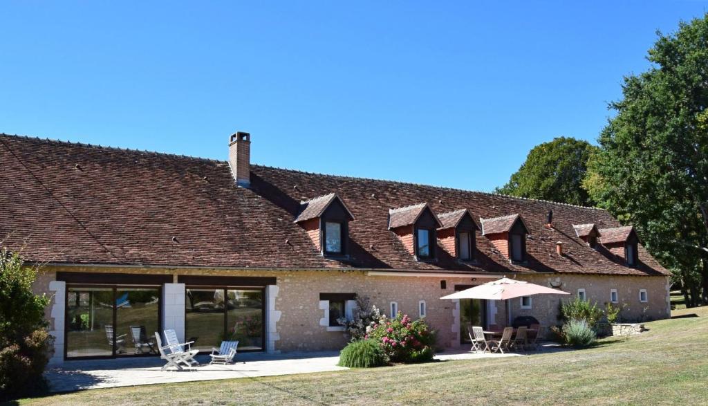 a building with a roof with chairs and an umbrella at Les Essarts pour 10+6 personnes sur 2 maisons in Châtillon-sur-Indre