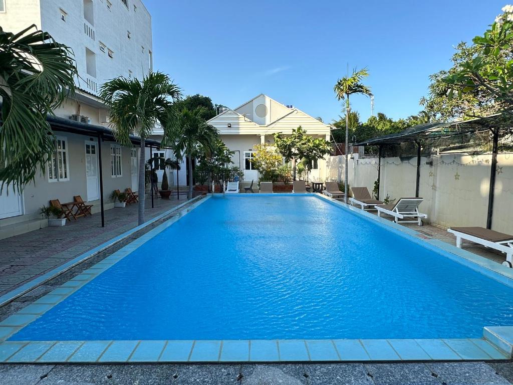 a large blue swimming pool next to a building at Pharos Guesthouse in Mui Ne