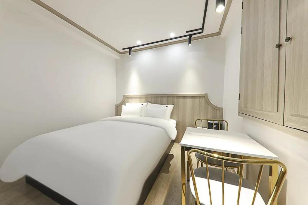 um quarto branco com uma cama e uma cadeira em From H Amor Hotel Masan em Changwon