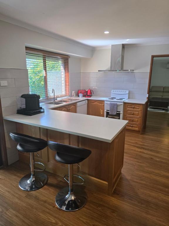 a kitchen with a large counter and two bar stools at The Golf Getaway in Myrtleford