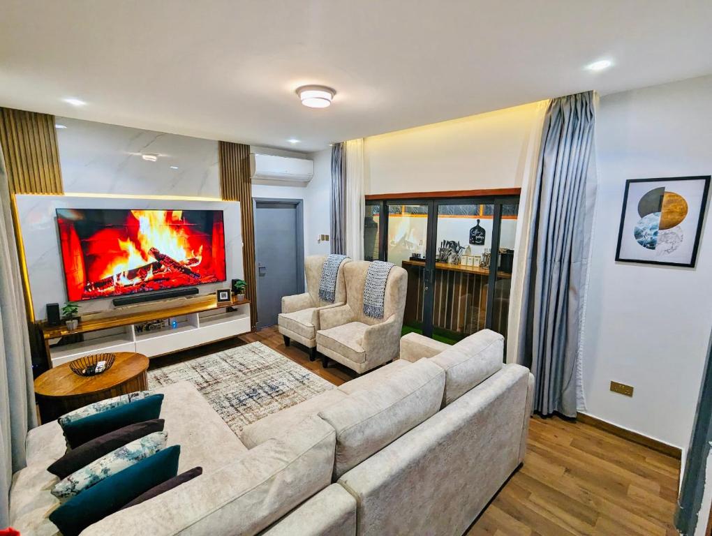 a living room with a couch and a flat screen tv at CozyHome 75”TV, 5mints from the Beach & City in Dar es Salaam