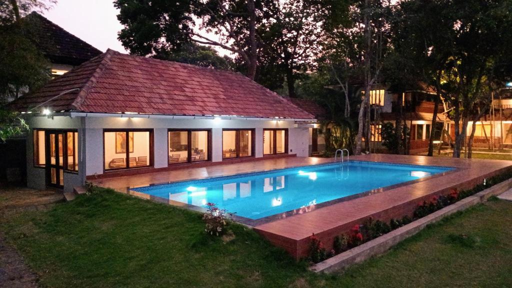 a swimming pool in front of a house at Shantitheeram Ayurveda Lakeside Heritage Resort in Alleppey