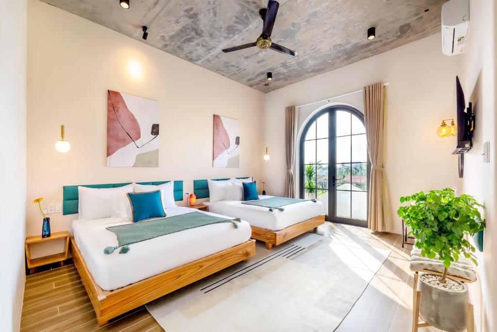 a bedroom with two beds and a ceiling fan at Hoi An Pinus Boutique in Tân Thành (1)