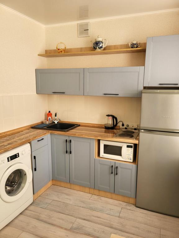 uma cozinha com armários cinzentos e uma máquina de lavar e secar roupa em Квартира em Balkhash