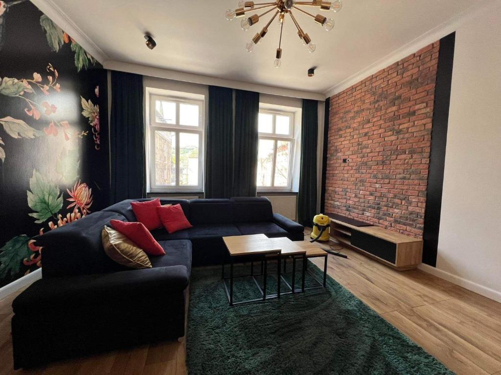 a living room with a blue couch and a brick wall at Kolejowa 4 Boutique Apartment in Nowa Ruda