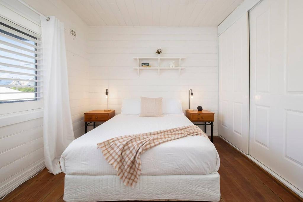 a white bedroom with a bed and two night stands at 'Sweet Caroline' A Classic Newcastle Hideaway in Newcastle