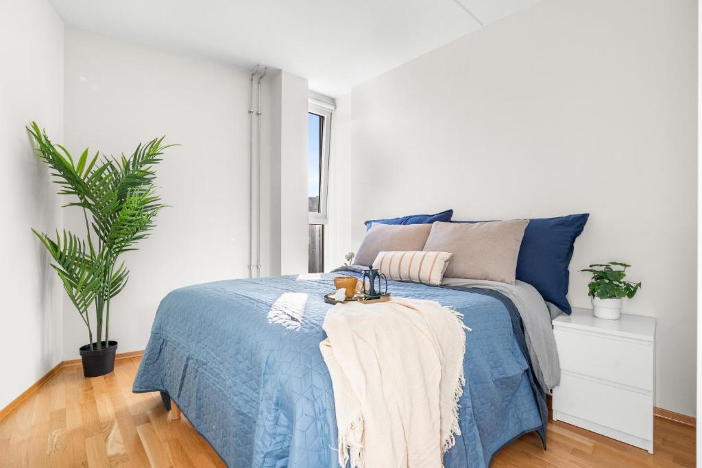 a bedroom with a blue bed and a plant at Top floor with balcony - Super central - 5 pax in Oslo
