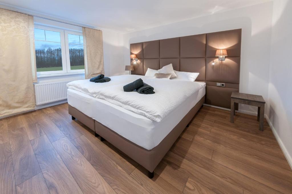 een slaapkamer met een groot wit bed en een raam bij Landgasthaus Krimpenfort in Lohne
