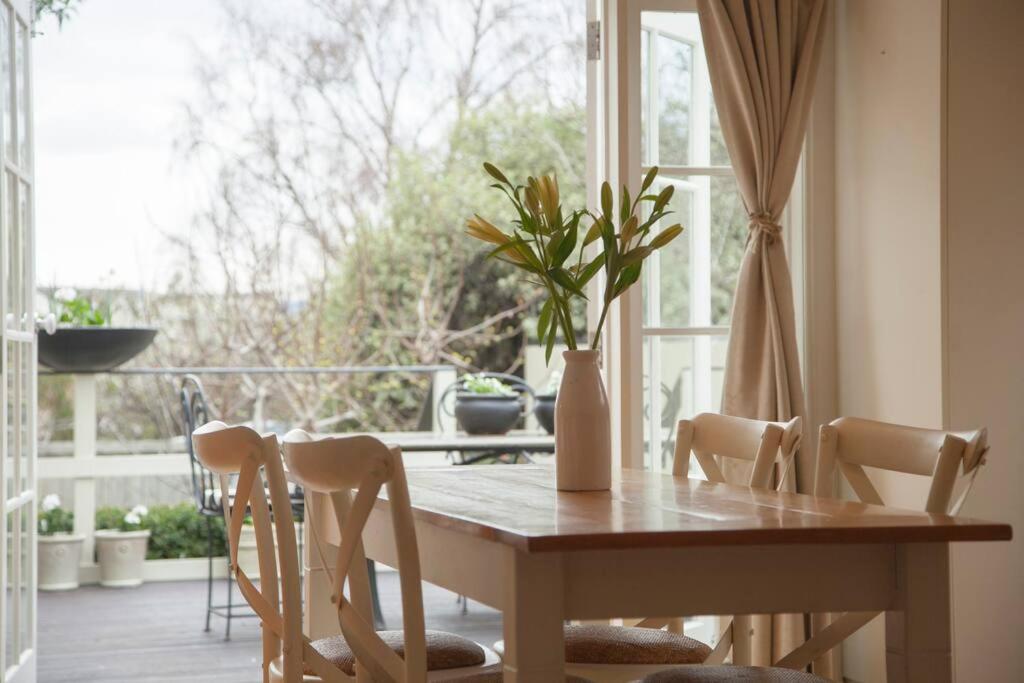 mesa de comedor con sillas y ventana en Writer's Cottage, luxurious oasis in the heart of North Hobart en Hobart