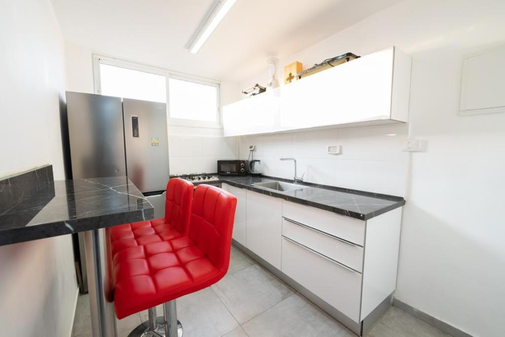 een keuken met rode stoelen in een witte keuken bij Beautiful apartment near Tel Aviv in Bat Yam