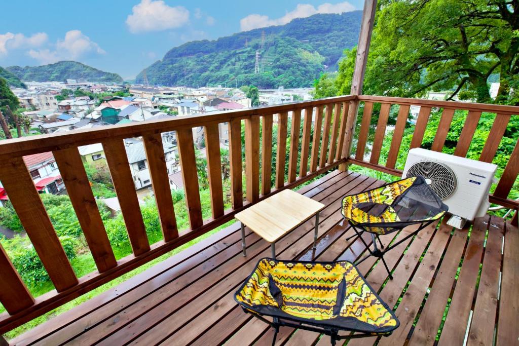 a balcony with two chairs and a fan on a mountain at ヒルトップ箱根　103 in Odawara