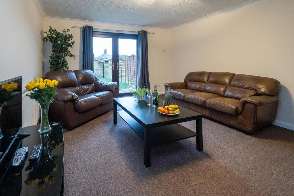 a living room with two leather couches and a coffee table at 52 Carr Avenue in Leiston