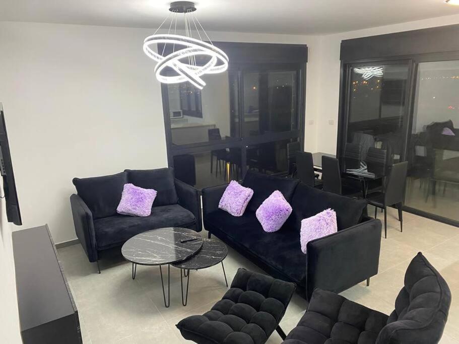 a living room with black couches and purple pillows at New- Luxury Glil Yam For Family 4 Rooms Parking in Herzliya