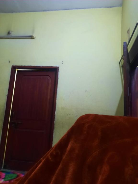 Schlafzimmer mit einem Bett und einer Holztür in der Unterkunft Vrindavan Home Stay,Varanasi. in Varanasi