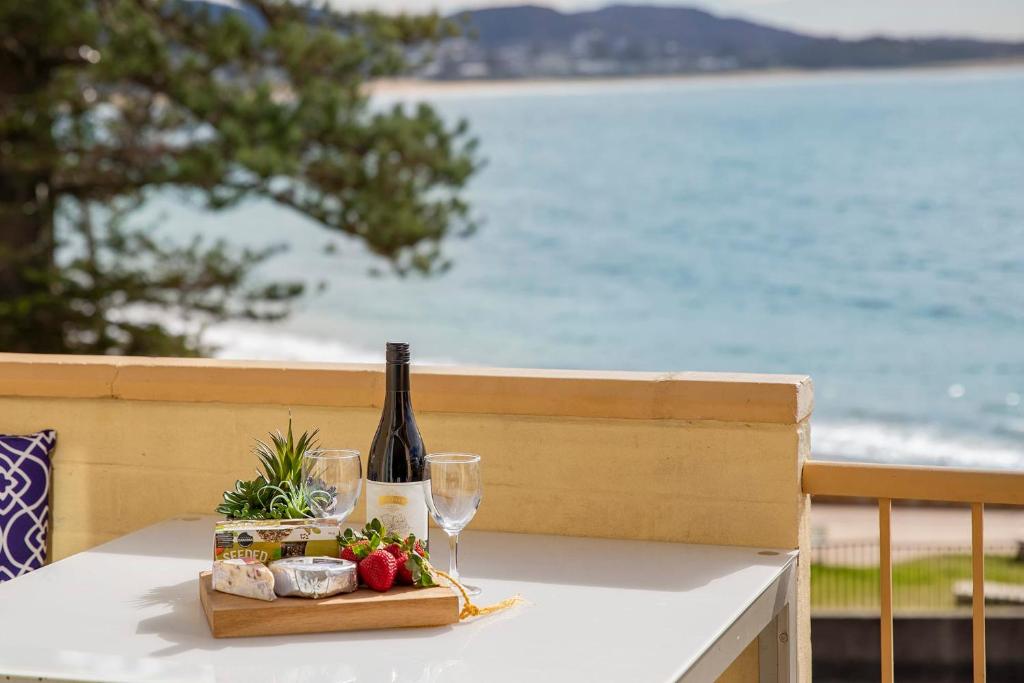 テリガルにあるOceans at Terrigal a Beachfront Oasisのワイン1本とグラスをテーブルに用意しています。