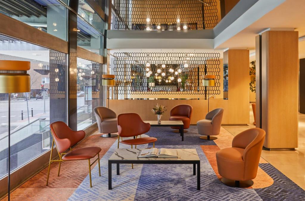 un vestíbulo de un hotel con sillas y mesas en Crowne Plaza Madrid - Centre Retiro, an IHG Hotel, en Madrid