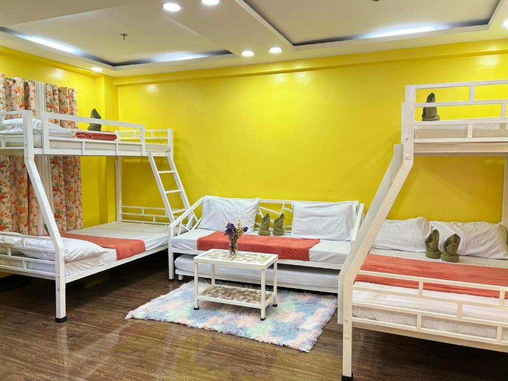 2 Etagenbetten in einem Zimmer mit gelber Wand in der Unterkunft Sassy's Place II in Baguio City