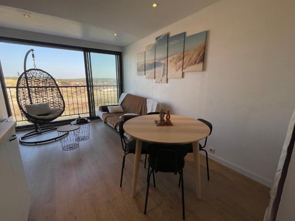 un salon avec une table et un canapé dans l'établissement Appartement de charme, vue océan, à Lacanau