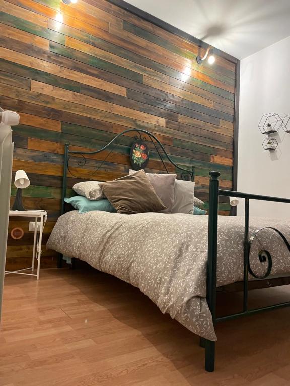 1 dormitorio con 1 cama con pared de madera en Casa Vacirca, en Niscemi