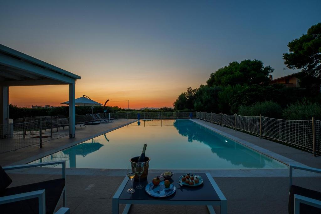 a pool with a table with a plate of food on it at Salicornia - Sea view villa with pool in Marsala