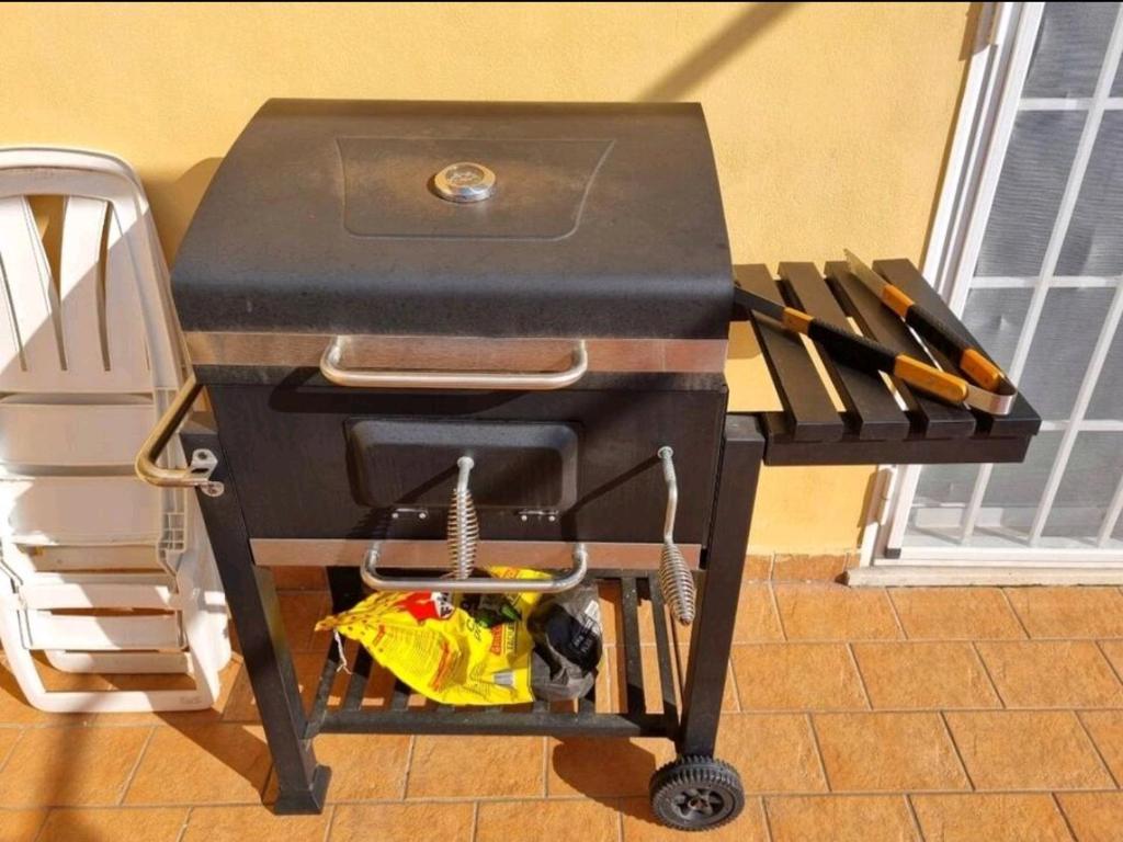 een grill zittend op een kar met enkele messen bij Attico con terrazzo Relax in Ladispoli