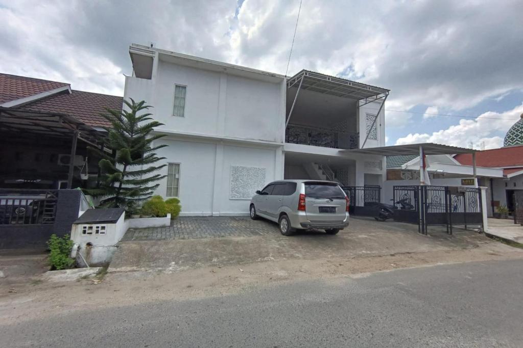 a car parked in front of a white house at OYO 93654 Gr Kost Kaladan in Rantau