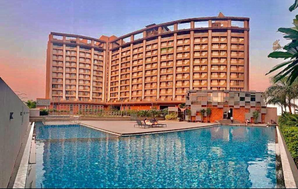 un hotel con piscina di fronte a un edificio di The Weekend Address Managed By Stay Cation a Surat