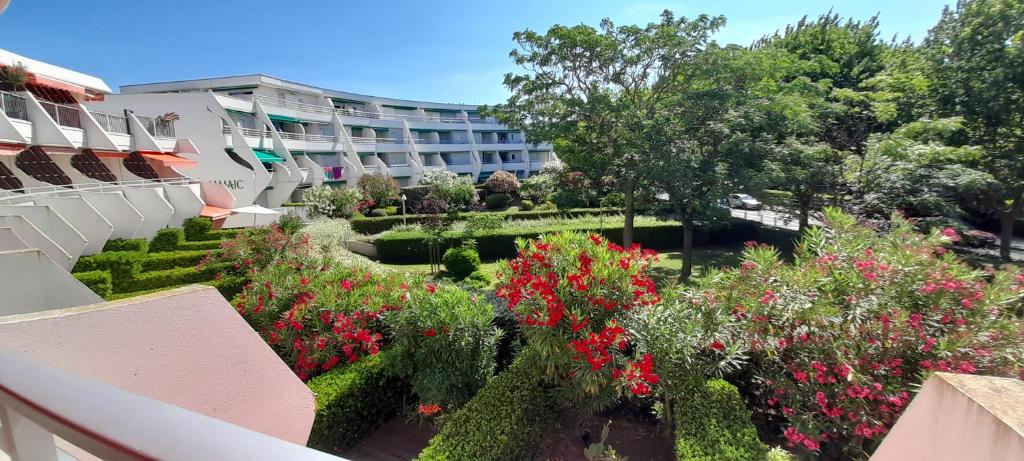 Elle offre une vue sur un jardin fleuri et un bâtiment. dans l'établissement Studio 25m2/côté couchant-plages & commerces, à La Grande Motte