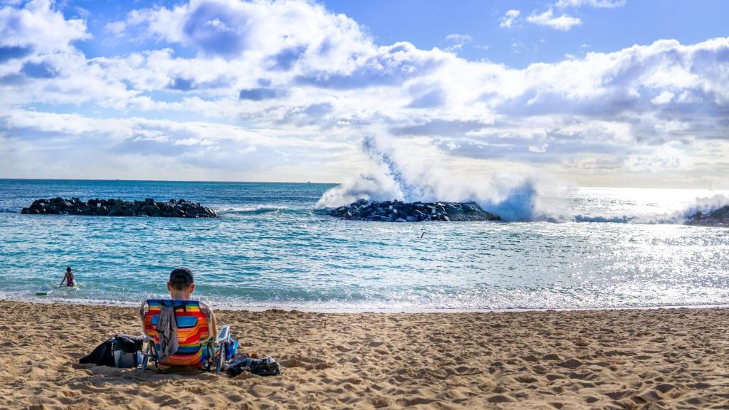 a man sitting in a life jacket on a beach at Ko Olina Beach Villas B610 in Kapolei