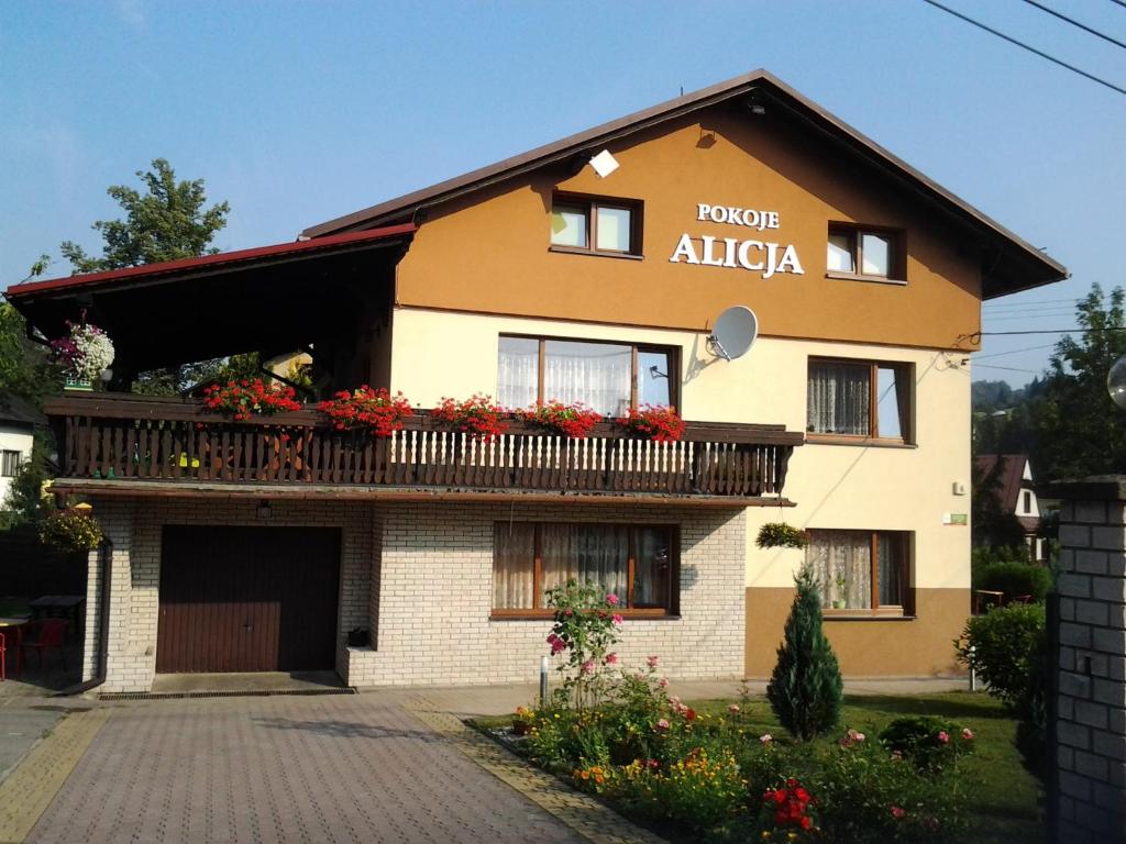 a building with a balcony with flowers on it at Pokoje Gościnne Alicja in Wisła