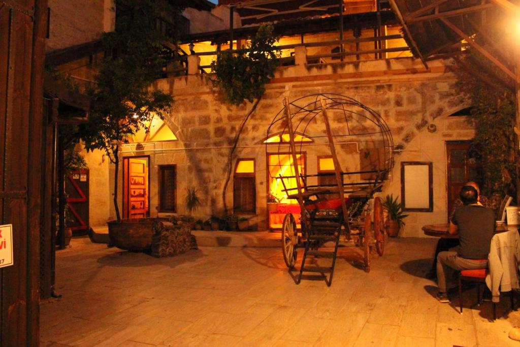 a man sitting in a room with a large room with a wheel at Tokmak Konukevi in Avanos