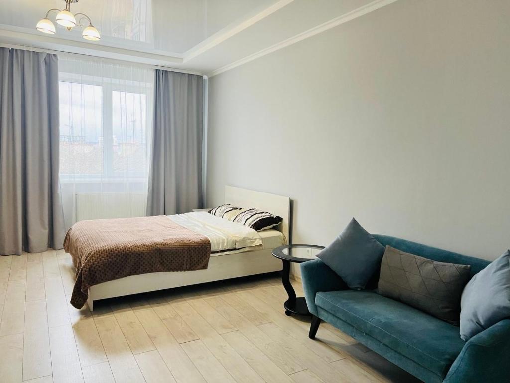 ein Schlafzimmer mit einem Bett, einem Sofa und einem Fenster in der Unterkunft Belveder Center Home in Iwano-Frankiwsk