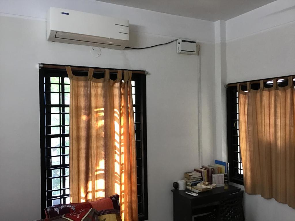 a living room with two windows with curtains at Chez Bussy in Puducherry