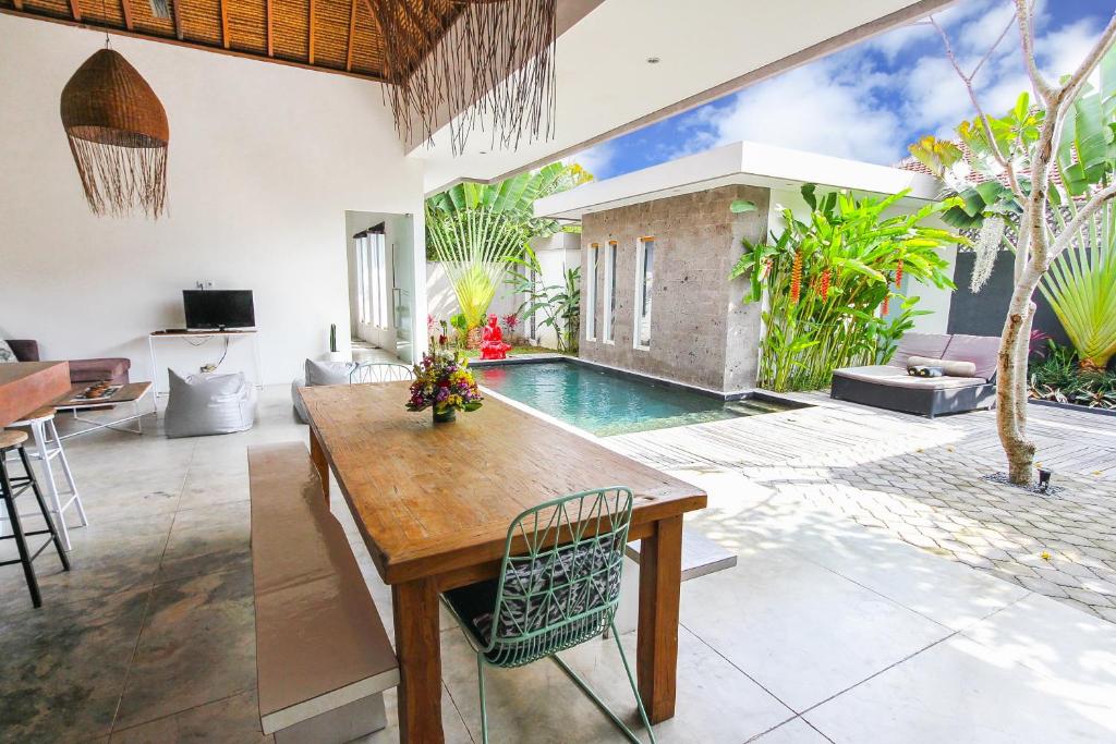 a living room with a table and a swimming pool at Villa Turtle in Seminyak