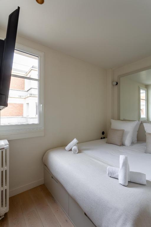 a white bedroom with a bed and a window at The Carla Suite Eiffel Tower View in Paris