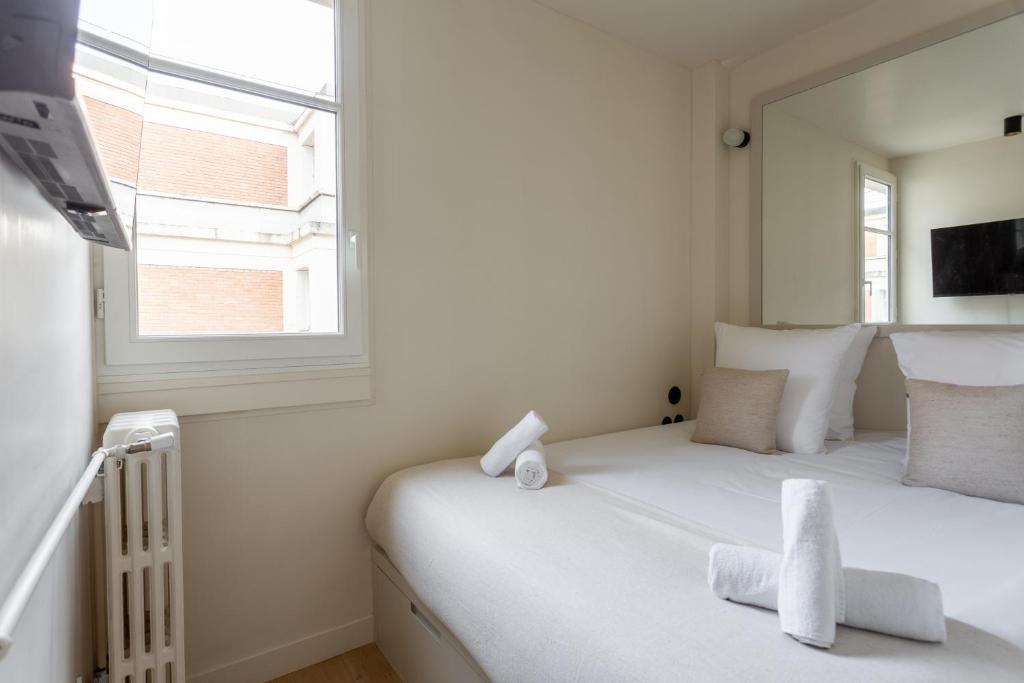 a white bedroom with a bed and a window at The Carla Suite Eiffel Tower View in Paris