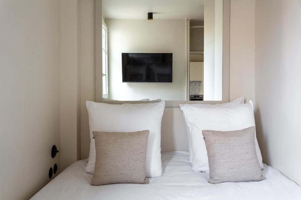 a room with white pillows on a bed with a window at The Carla Suite Eiffel Tower View in Paris