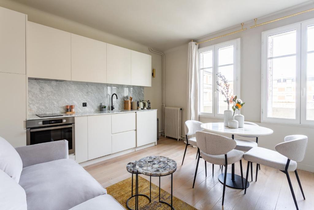 a kitchen with white cabinets and a table and chairs at The Carla Suite Eiffel Tower View in Paris