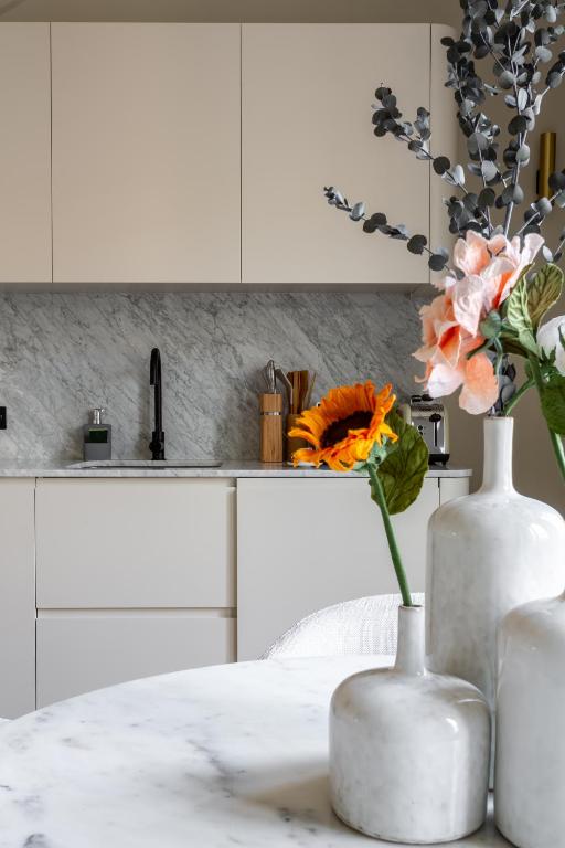 two white vases with flowers on a counter in a kitchen at The Carla Suite Eiffel Tower View in Paris