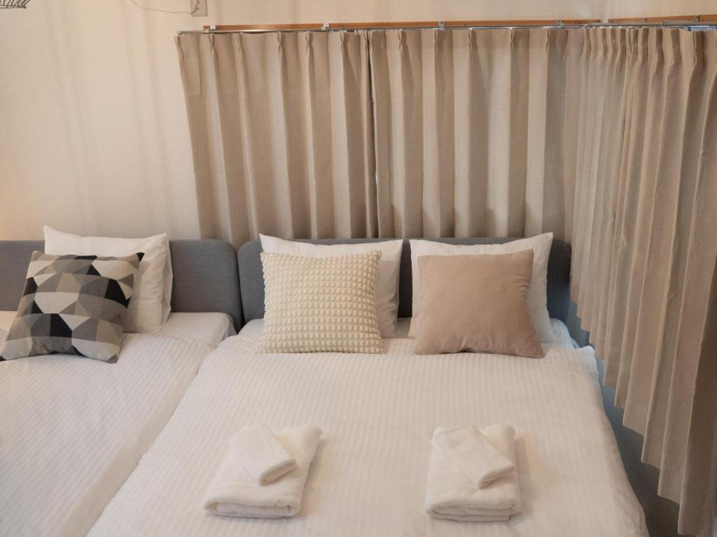 1 dormitorio con 2 camas con sábanas y almohadas blancas en Lido North Shinagawa, en Tokio