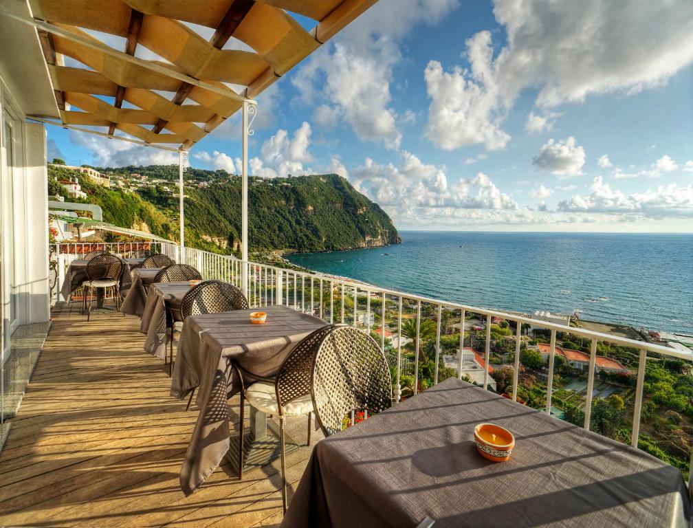 a balcony with tables and chairs and the ocean at Hotel Imperamare in Ischia