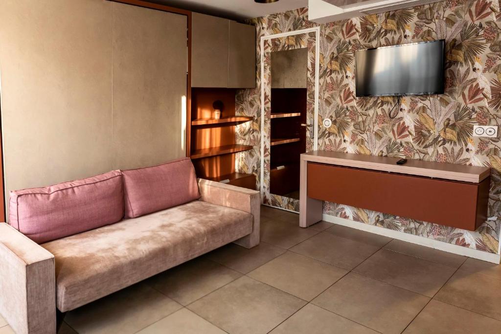 a living room with a couch and a tv on a wall at MULTIRESIDENCE L&#39;ELYSEE Paris in Paris