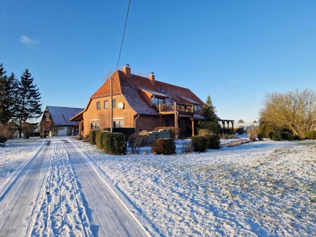 uma casa numa estrada coberta de neve na frente em Ferienwohnung Lindenallee em Neu Poserin