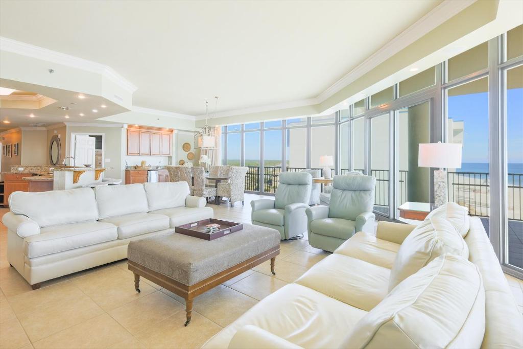 ein Wohnzimmer mit weißen Möbeln und Glasfenstern in der Unterkunft Phoenix West 609 condo in Orange Beach